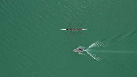 Aerial-close-to-high-shot-over-a-rowing-team-with-a-coach-on-a-boat-lake-France